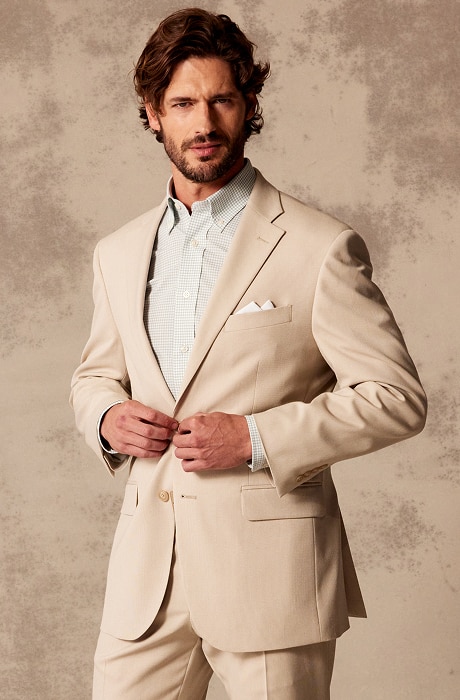 Man wearing a tan suit and checkered dress shirt