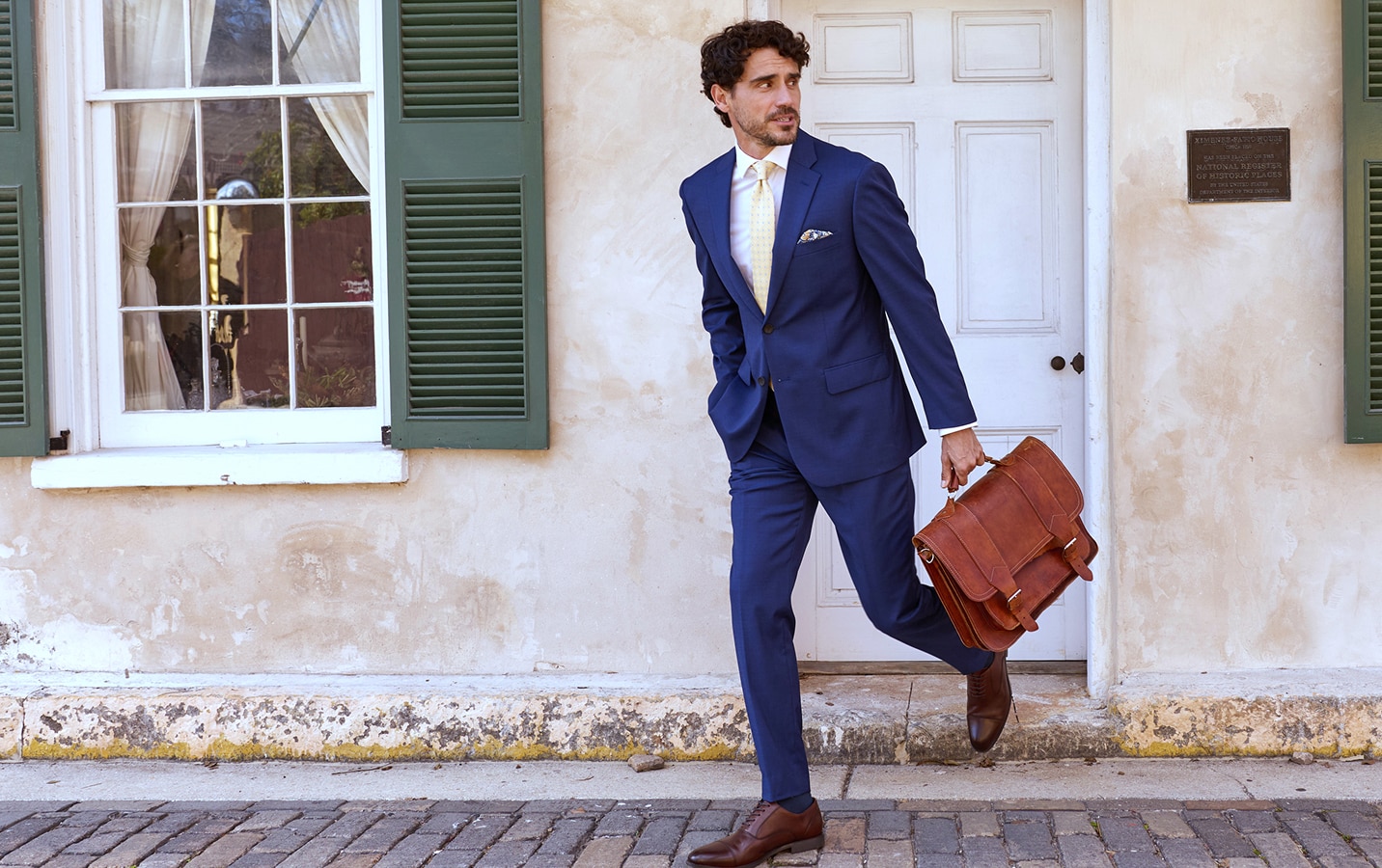 Man in navy suit carrying a brown leather briefcase