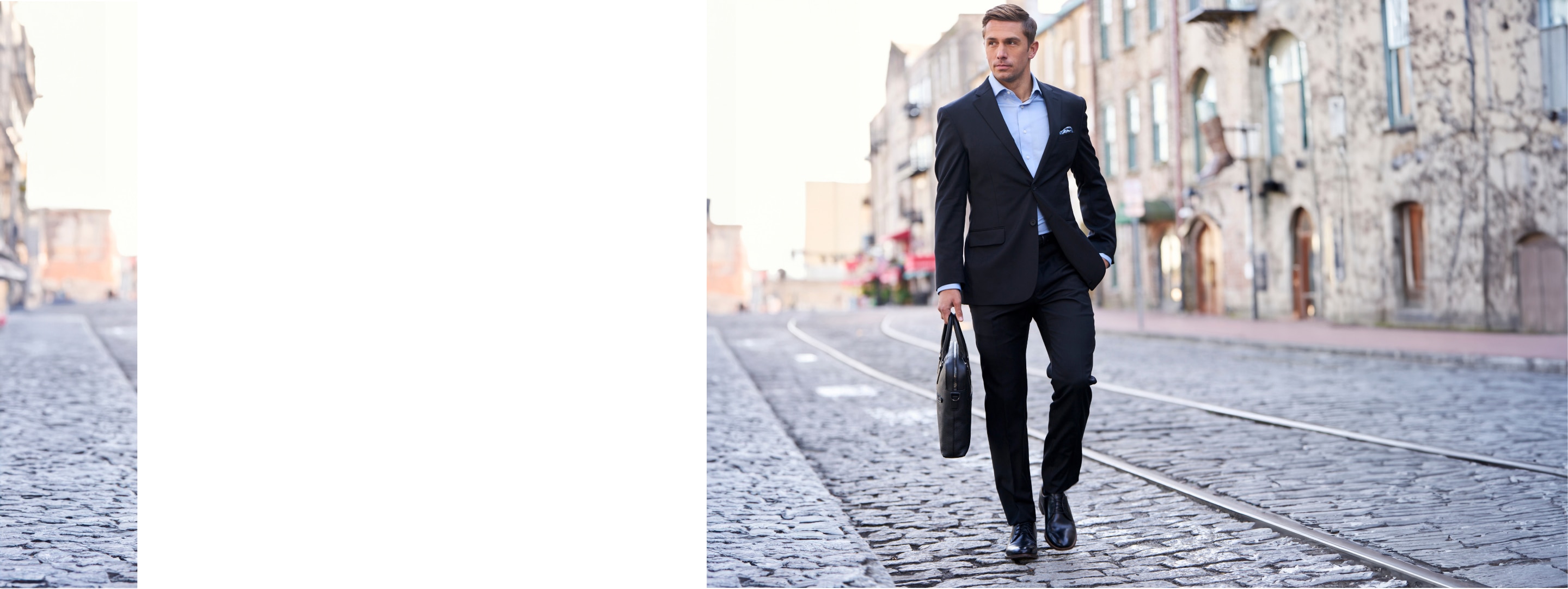 Man in a navy suit walking on a cobblestone street.