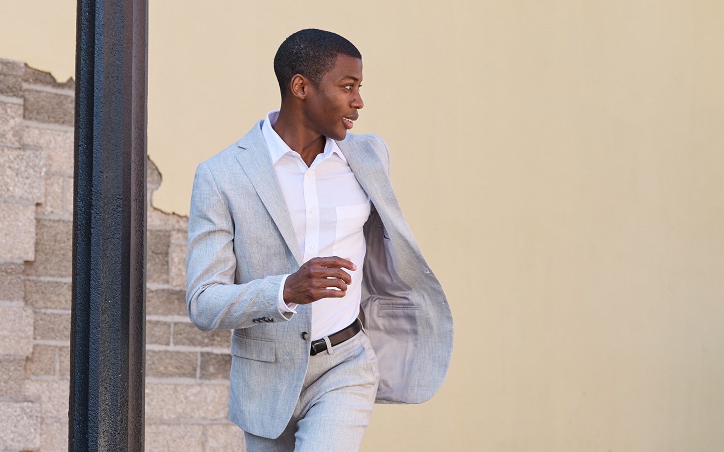 Man in a light grey suit walking outdoors