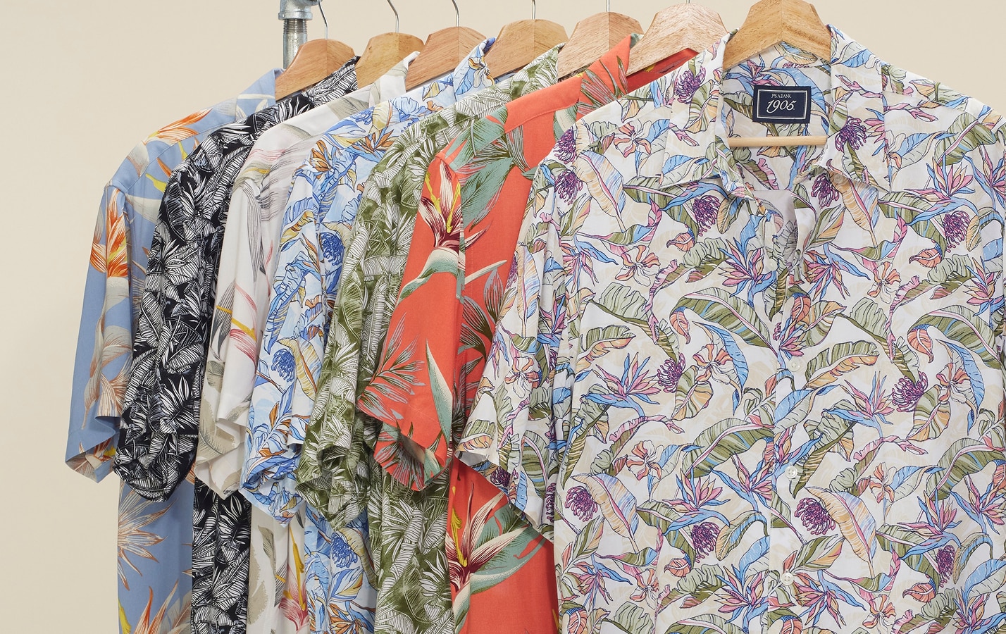 Short-sleeve casual shirts with tropical and floral prints on wooden hangers