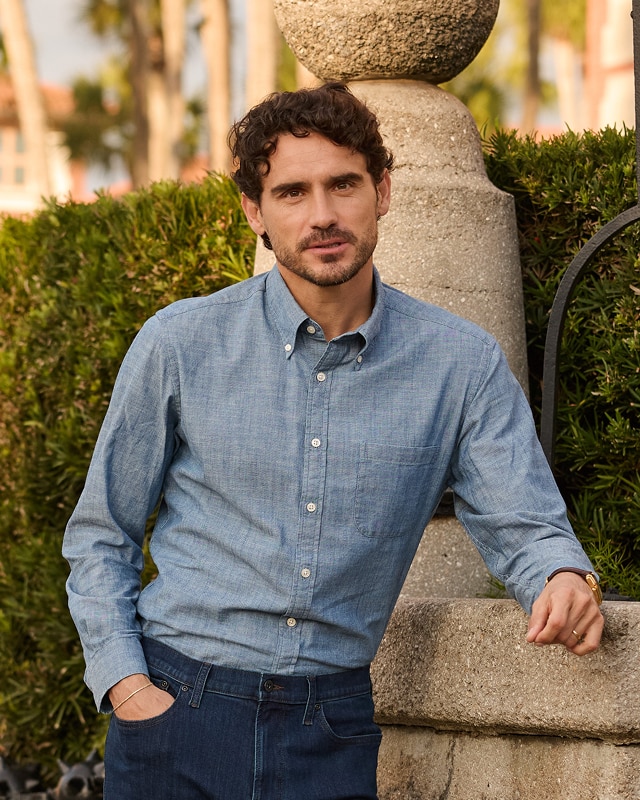 Man in a light blue button-down shirt and dark jeans