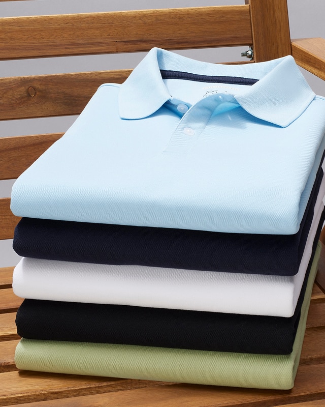 Stack of folded polo shirts in light blue, navy, white, black, and light green