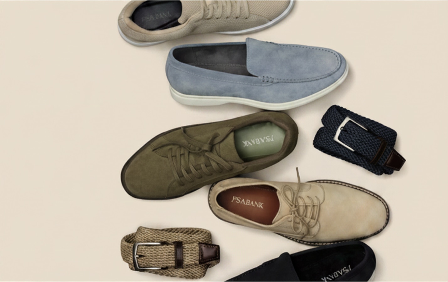 Assortment of mens shoes and woven belts on a beige background