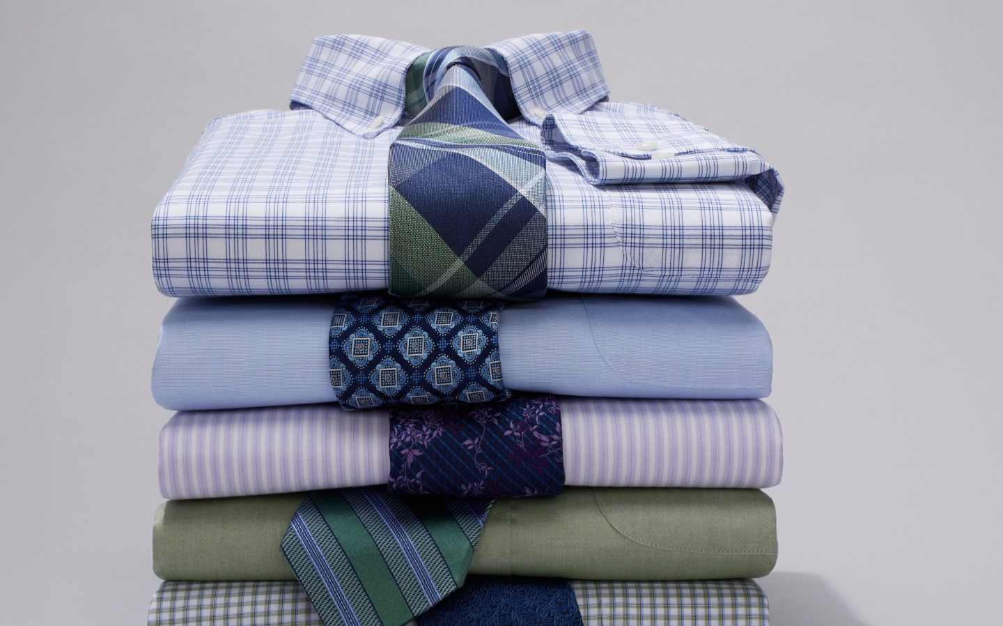 Stack of folded dress shirts with coordinating neckties