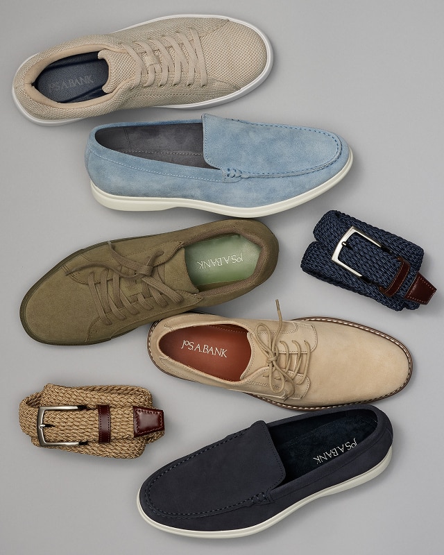 Assortment of mens shoes and woven belts on a beige background