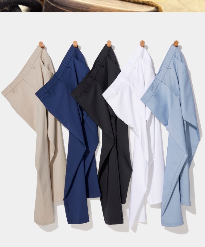 Five pairs of mens dress pants in beige, navy, black, white, and light blue hanging on wooden pegs