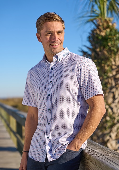 Man wearing a patterned short-sleeve casual shirt on a sunny boardwalk