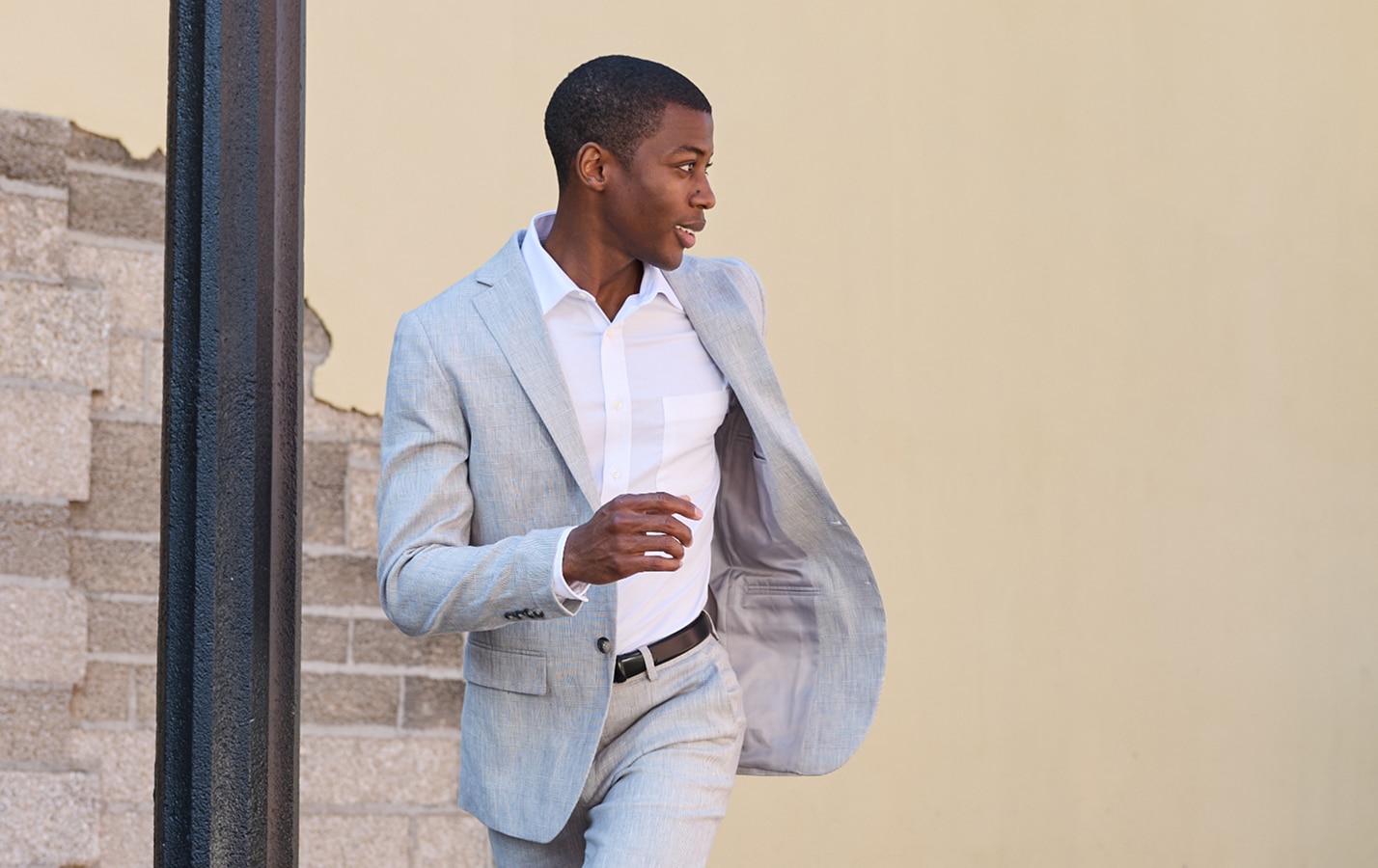 Man in a light grey suit walking outdoors