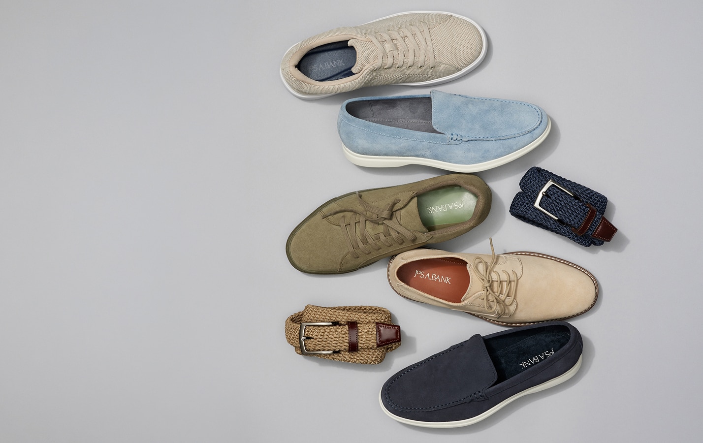 Assortment of casual shoes and woven belts on a light gray background