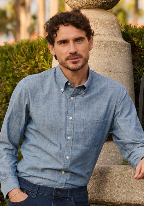 Man in a light blue chambray casual shirt and jeans outdoors