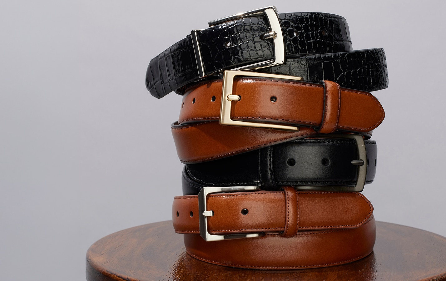 Stack of rolled leather belts in black and brown with metal buckles
