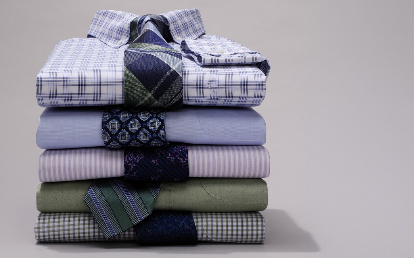 Stack of folded dress shirts with coordinating neckties