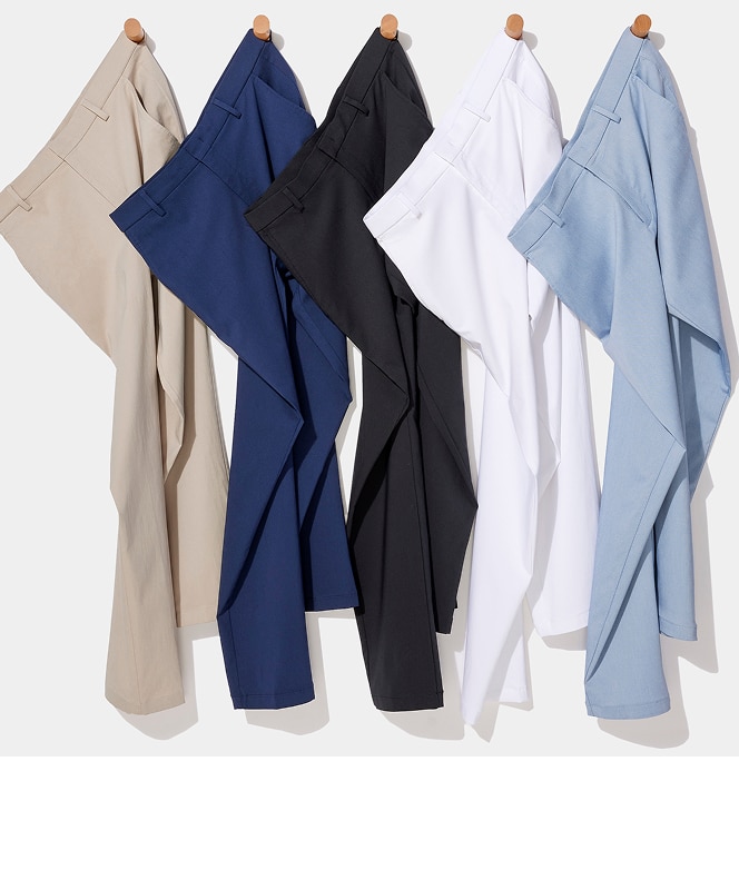 Five pairs of pants hanging on wooden wall pegs in khaki, navy, black, white, and light blue