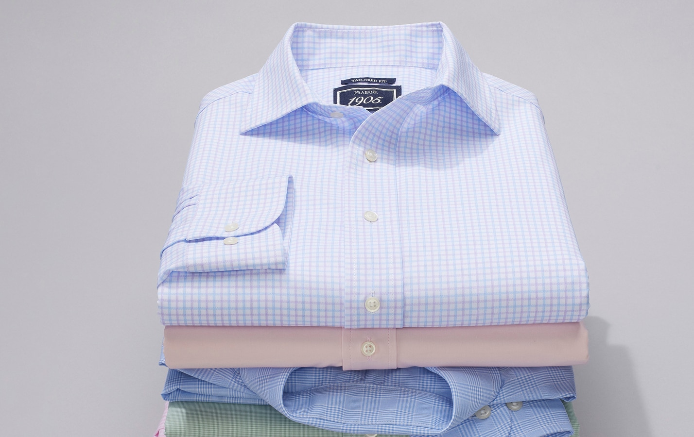Stack of folded dress shirts in assorted colors and patterns