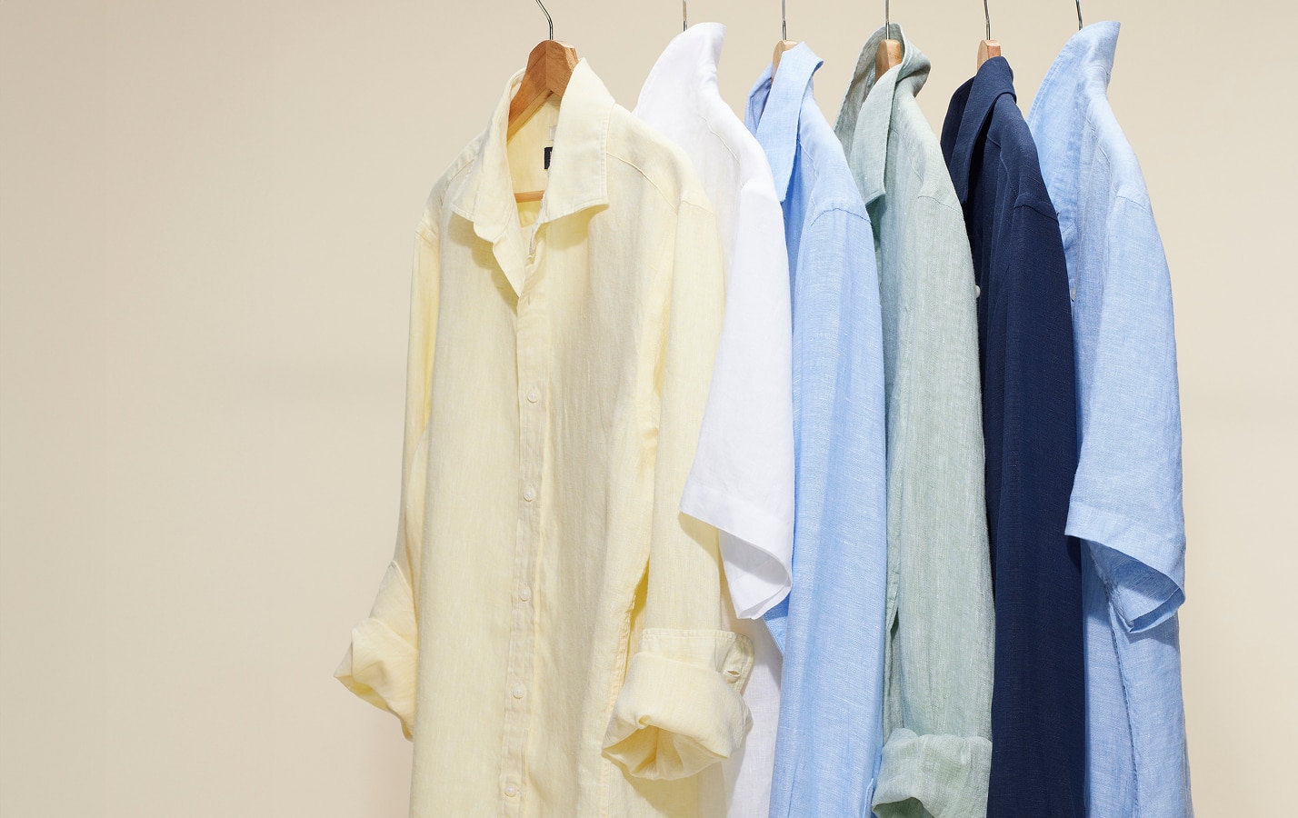 Casual shirts in white, yellow, and blue hanging on a rack