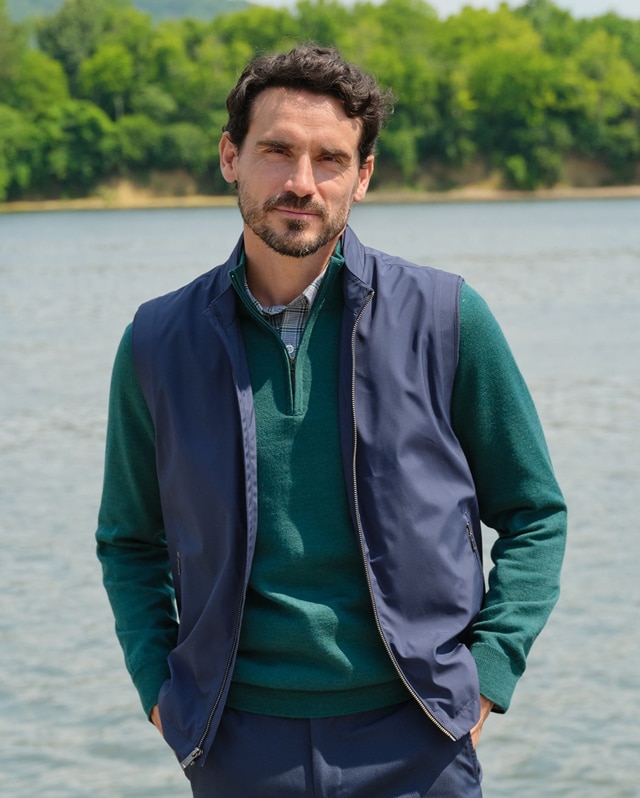 Man wearing a navy vest over a green sweater