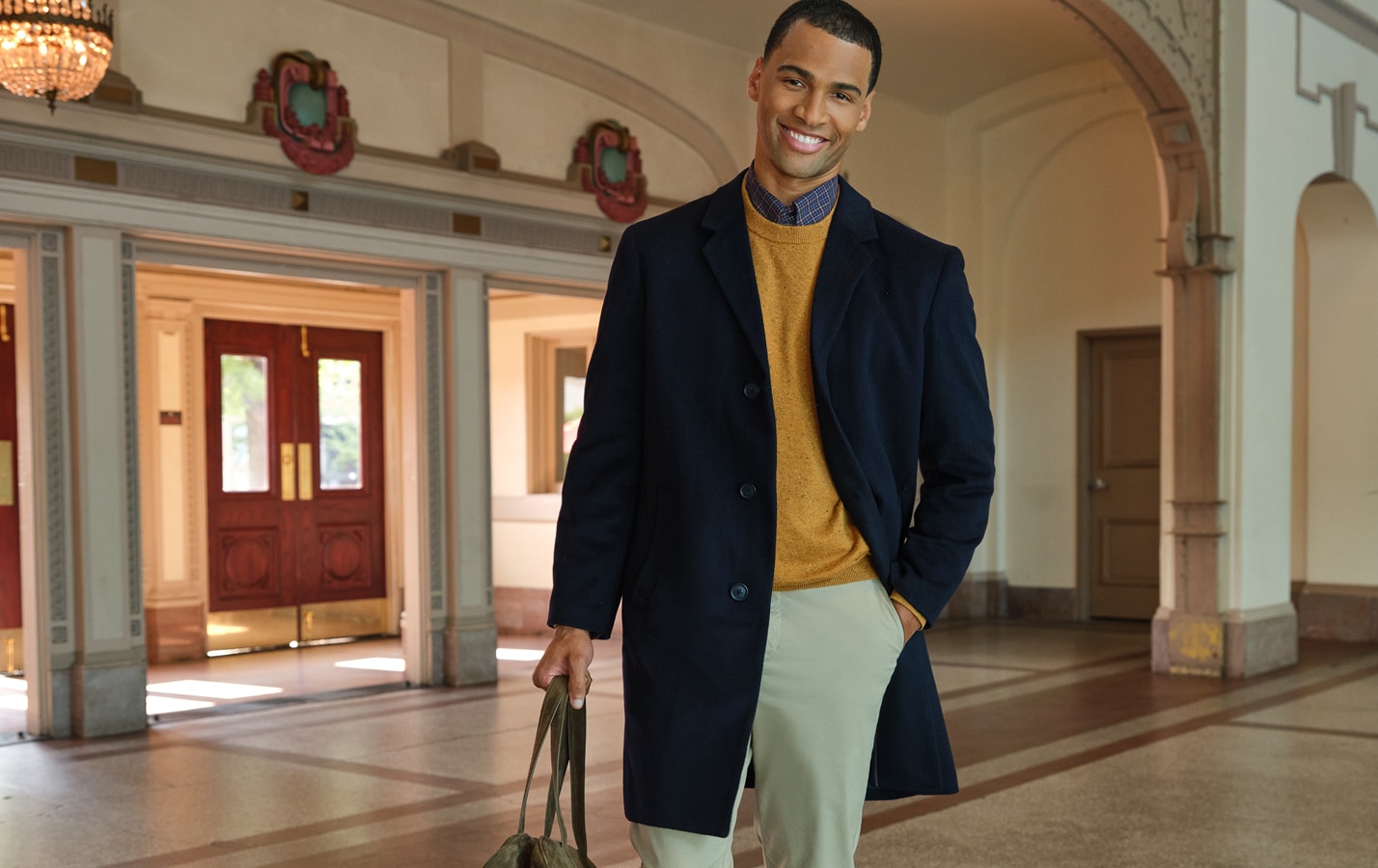Man wearing a navy overcoat over a mustard sweater