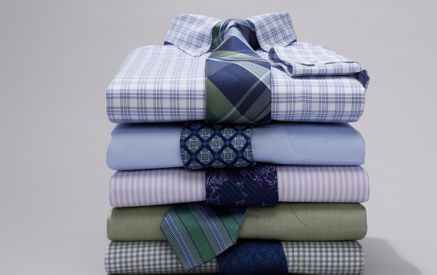 Folded dress shirts with patterned ties draped on each