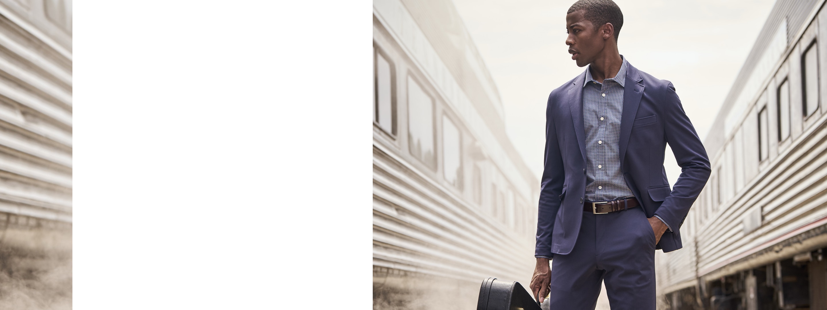 Man wearing a navy clearance suit standing between two trains