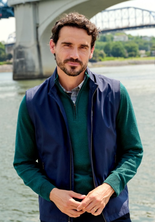 Man wearing a navy vest over a green sweater