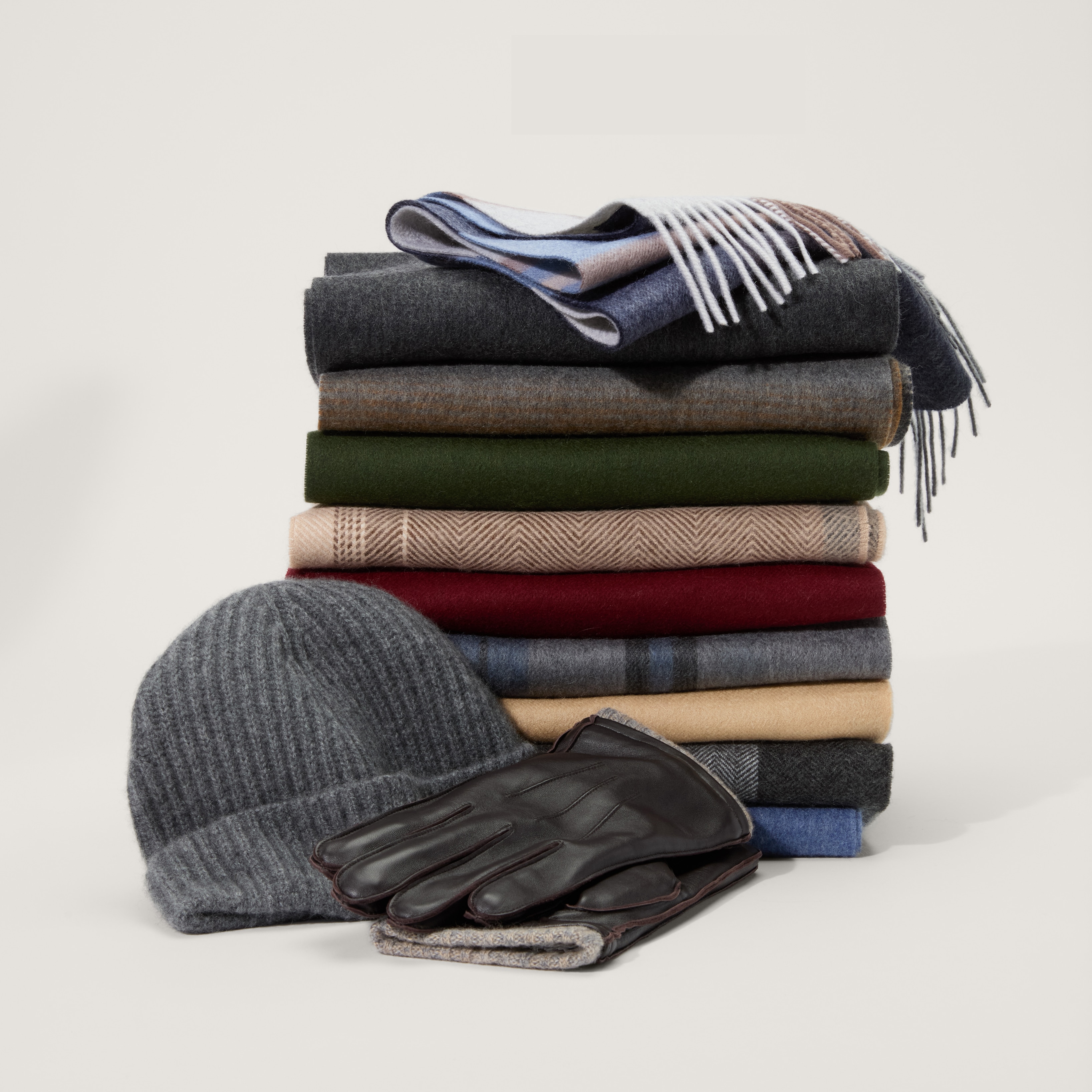 Folded scarves with a gray knit beanie and brown leather gloves
