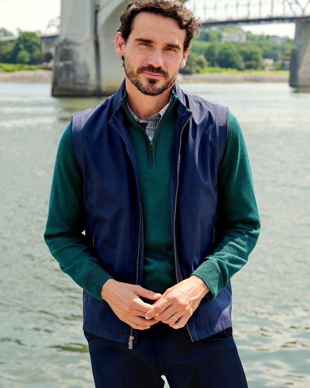 Man wearing a navy quilted vest over a green sweater