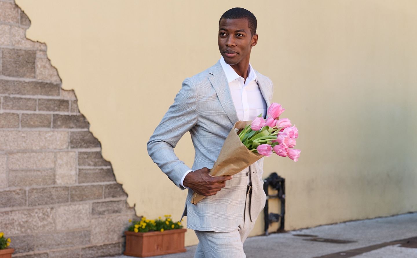 Man in light grey suit carrying pink tulips