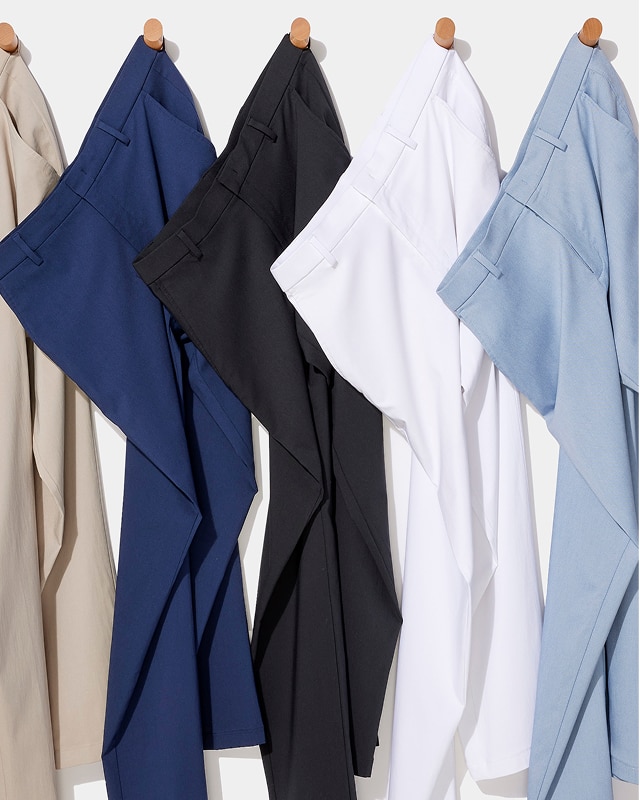 Five pairs of pants in tan, navy, black, white, and blue hanging on hooks