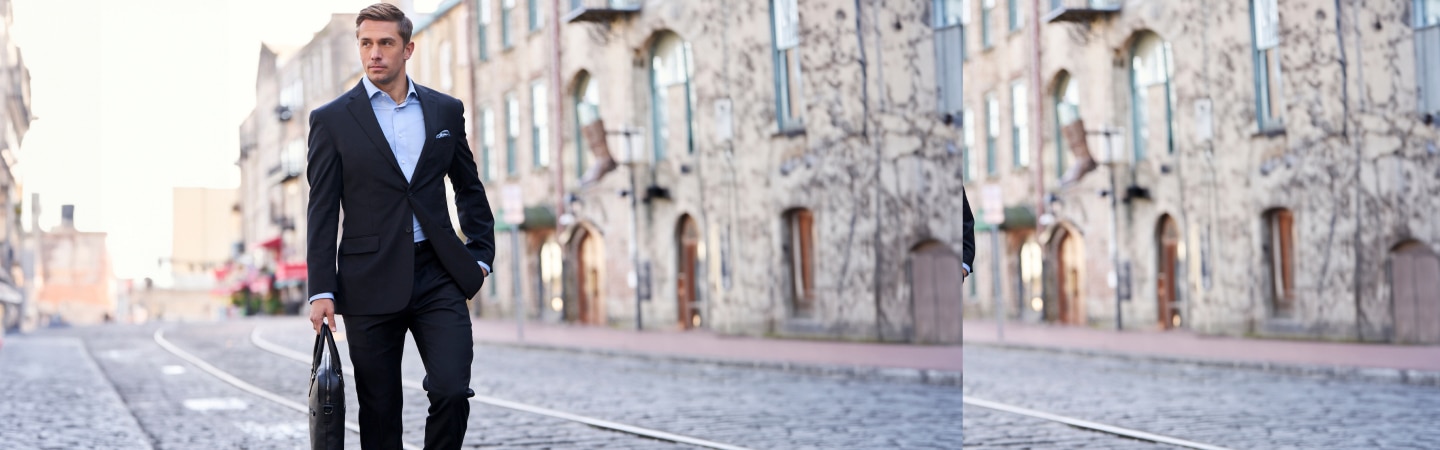 Man in a navy suit carrying a briefcase while walking down a cobblestone street