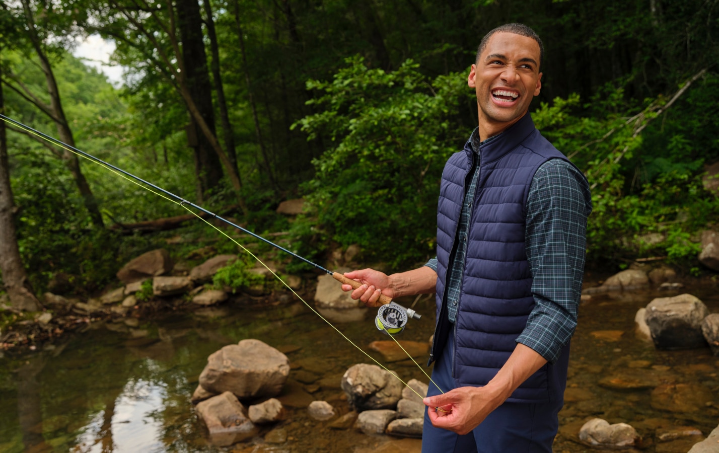 Man wearing a navy vest while fly fishing